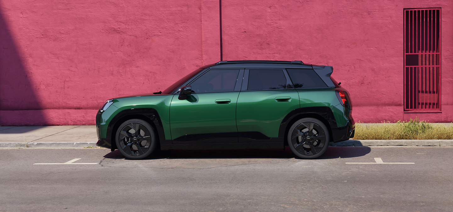 Vue latérale du MINI Aceman Electric British Racing Green avec toit noir en ville.