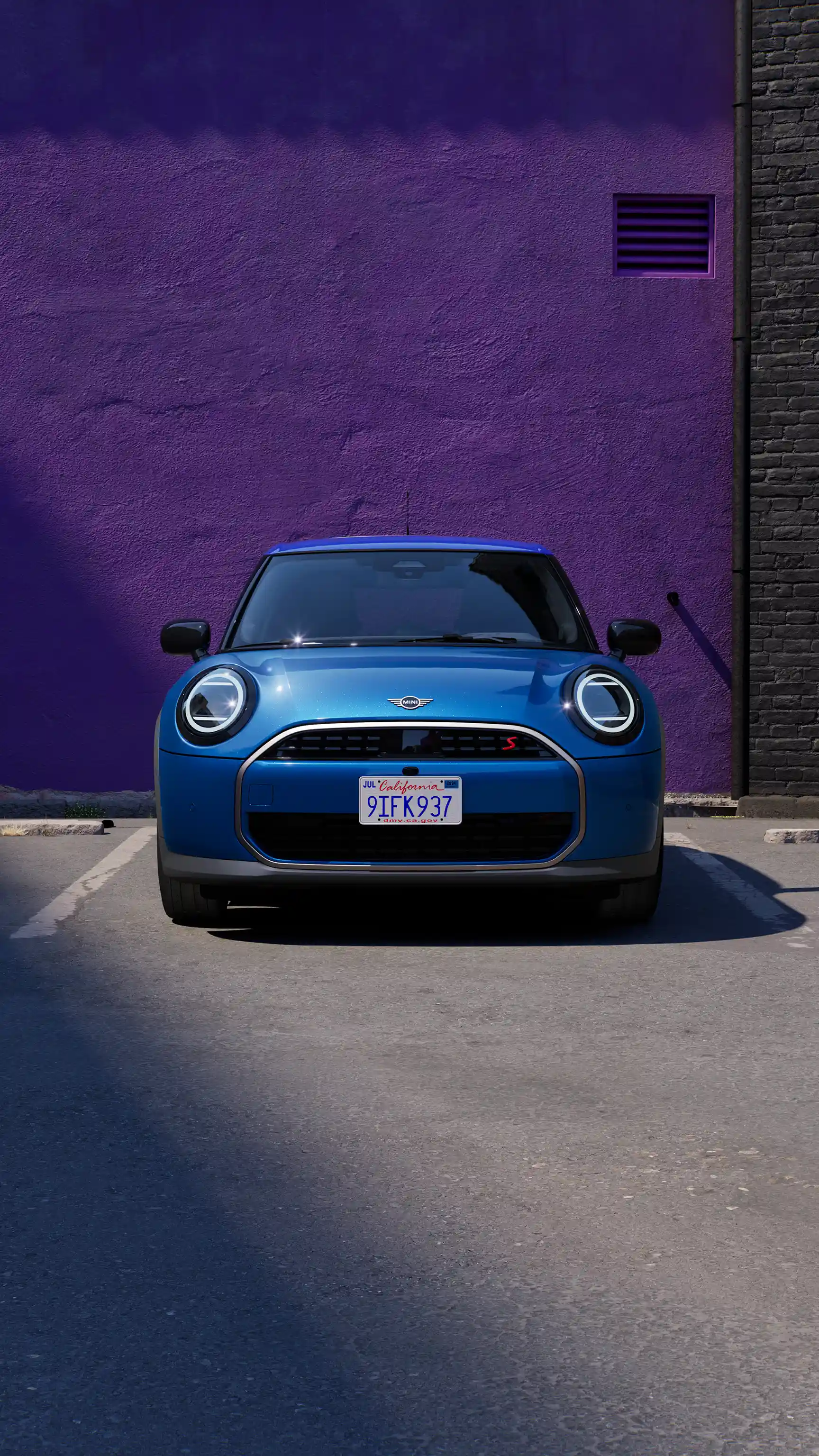 MINI Cooper, vue de face, stationnée devant un mur violet. 