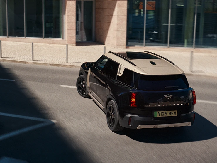 Vue du dessus arrière du MINI Countryman Electric Midnight Black avec toit Vibrant Silver en stationnement,