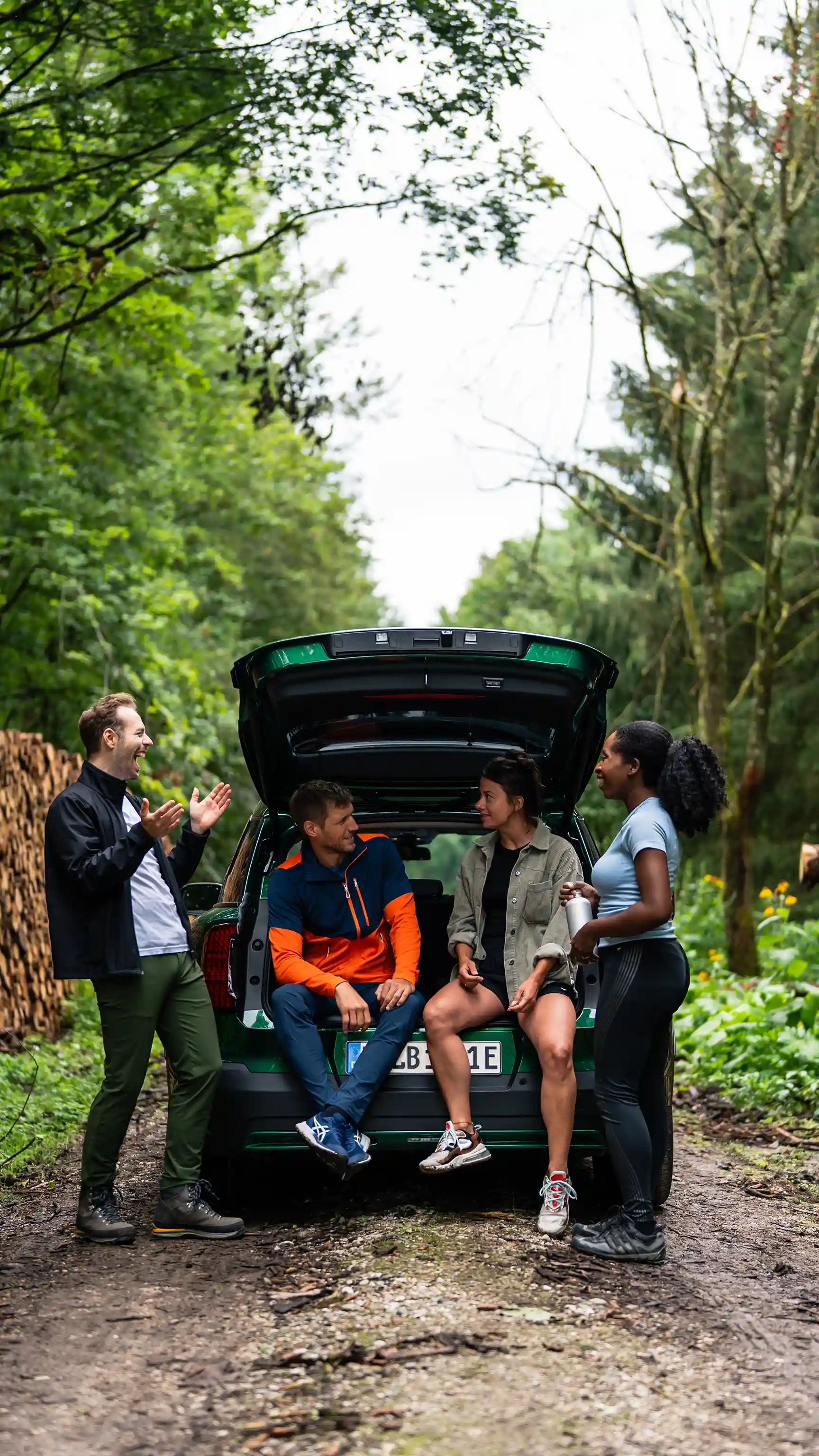 Group of people gathered at the open boot of a MINI Countryman in a forest setting.