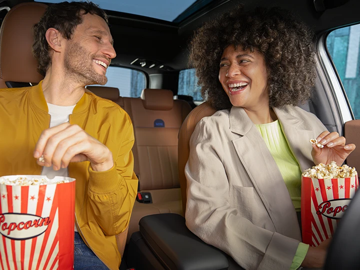 Deux personnes assises à l’intérieur d’un véhicule en train de déguster du pop‑corn.